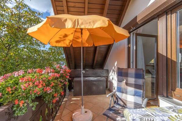 Un espace patio aménagé avec une table et des chaises, une pergola en bois et un grand parasol.