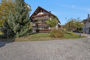 Un bâtiment à deux étages doté d’un balcon, entouré d’une allée en gravier et d’un petit jardin.