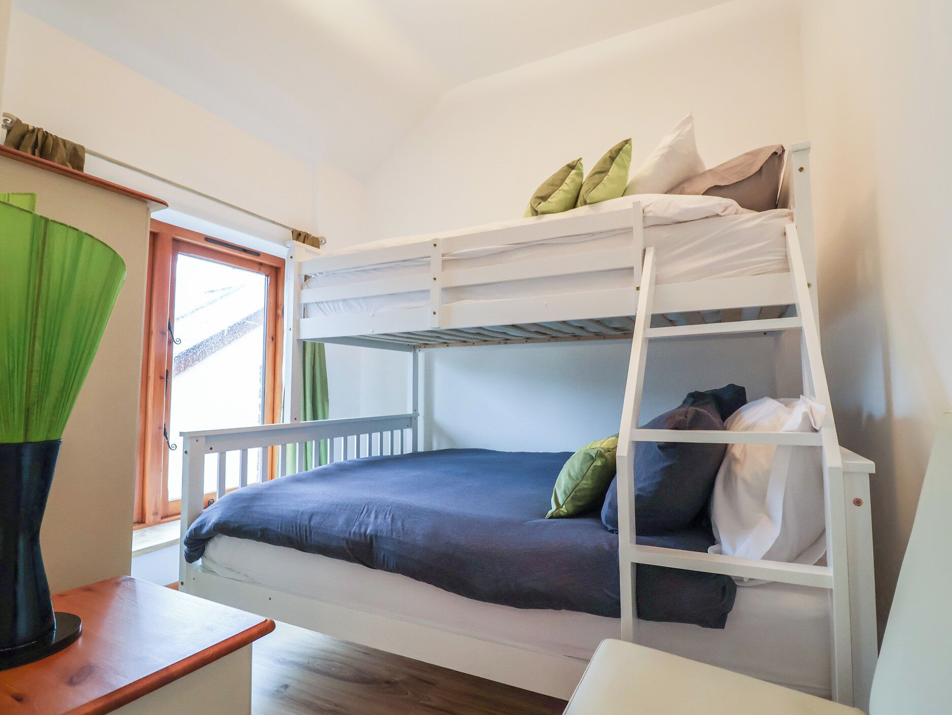 A bunk bed with a desk and a window.