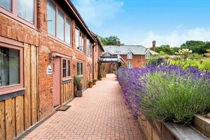 A brick building with a wooden fence, a paved walkway, and a garden with lavender. - Lime Cottage (Exeter)