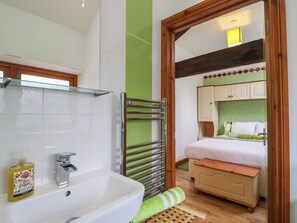 A bathroom with a white sink, a glass shelf, and a bottle of liquid soap. - Lime Cottage (Exeter)