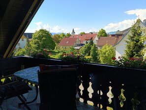 A balcony with a table and chairs, overlooking a residential area with houses and greenery.