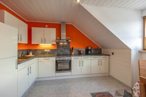 Une cuisine avec des meubles blancs, une cuisinière et une machine à café.