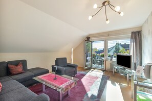 Un salon moderne avec un canapé, un fauteuil et une table basse en verre.