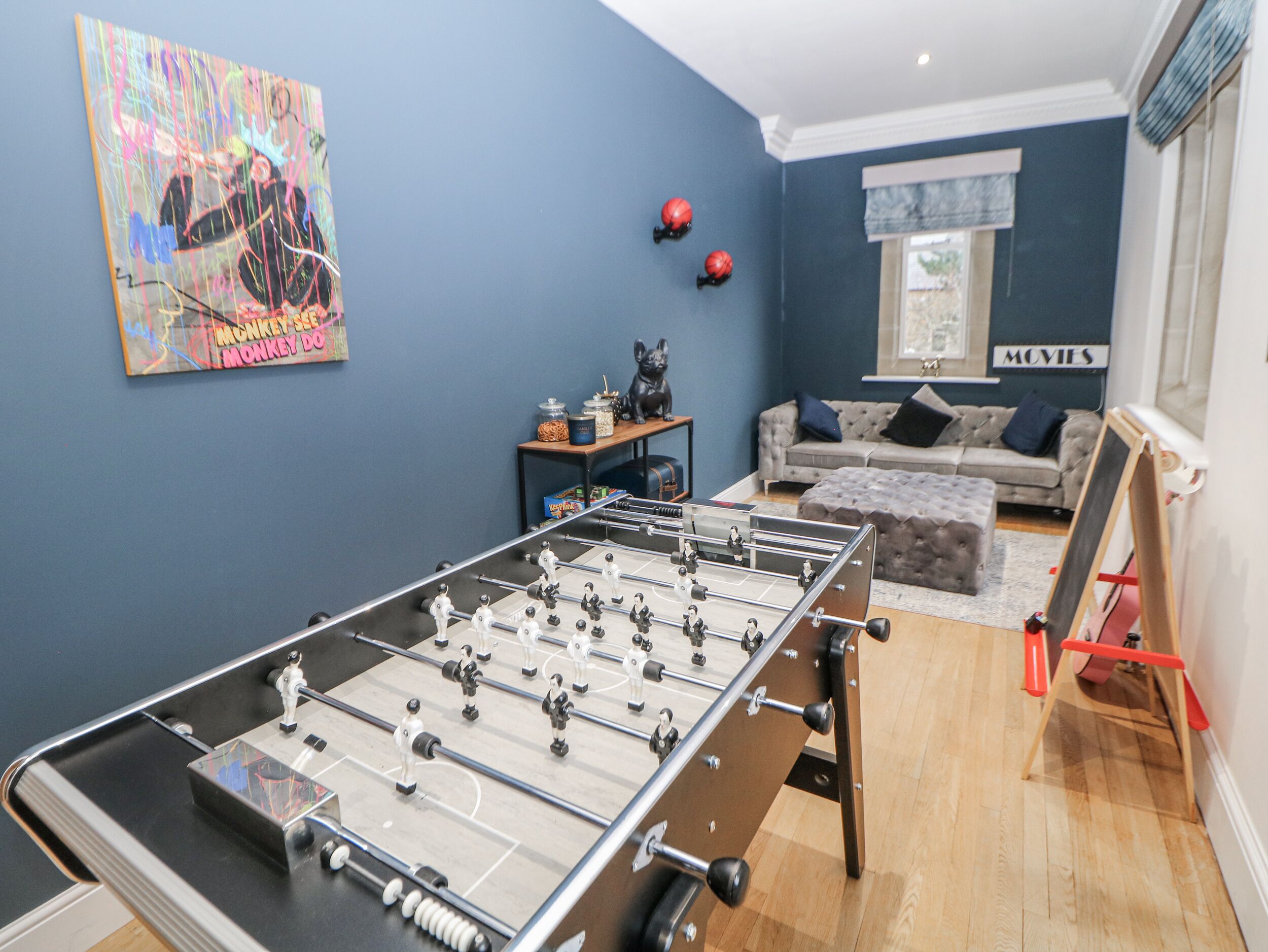 Una habitación con mesa de fútbol, un sofá, una mesa de centro y un cuadro en la pared.