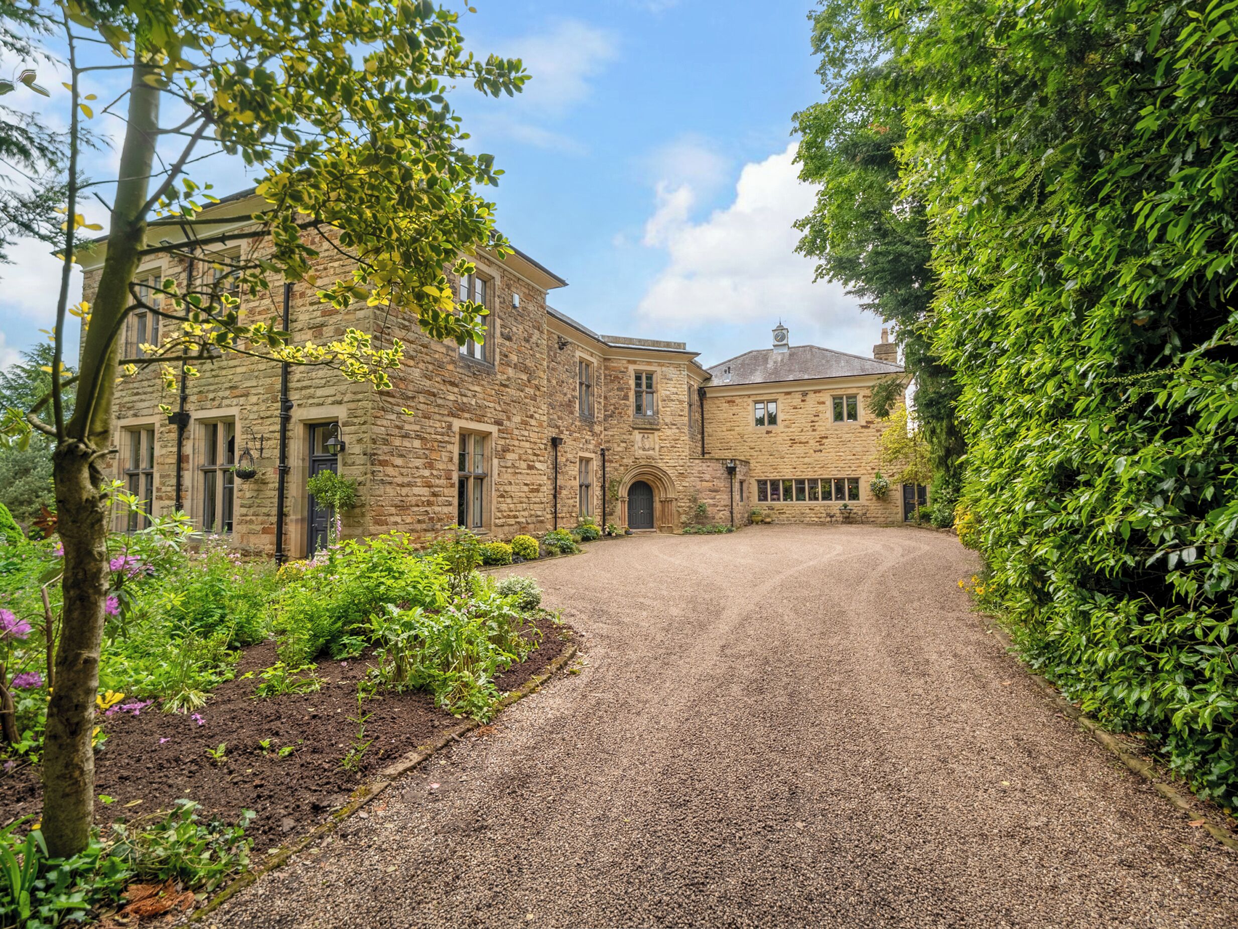 A stone building with a gravel driveway leading to a gated entrance.