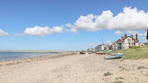 Une plage avec un bâtiment, des bateaux et un ciel dégagé.