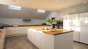 Une cuisine moderne dotée d’un îlot central, d’appareils électroménagers intégrés et de fenêtres de toit.