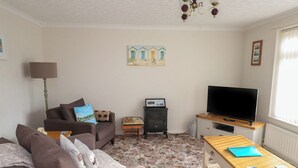 Una sala de estar con un sofá, un televisor, una mesita, una lámpara y un cuadro en la pared.
