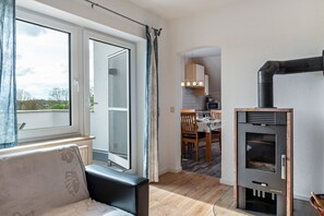 Ett modernt kök med en inbyggd spis, en matplats med trästolar och ett stort fönster med gardiner.