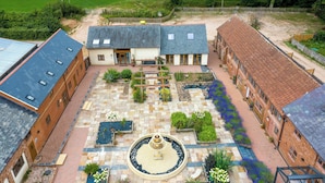 A courtyard with a central fountain, surrounded by brick buildings with multiple windows and a paved walkway. - Poppy Cottage (Exeter)