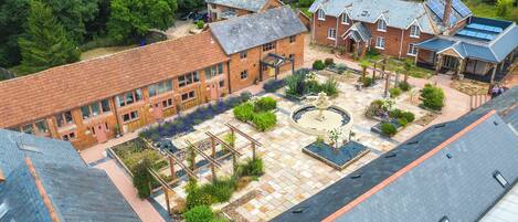 A courtyard with a brick building, a circular garden, and a small pond.