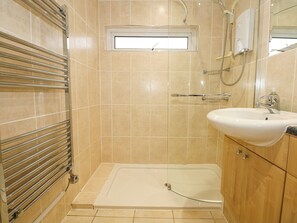 A bathroom with a walk-in shower, a sink, and a window above the shower. - Anchor Watch (Porthmadog)