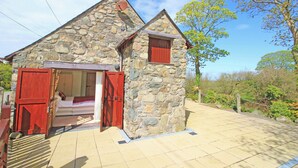 Une petite maison en pierre avec une porte en bois et un petit abri attenant.