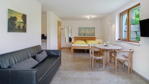 Ein modernes Zimmer mit einer Couch, einem Bett, einem Esstisch mit Stühlen und Kunstwerken an den Wänden.