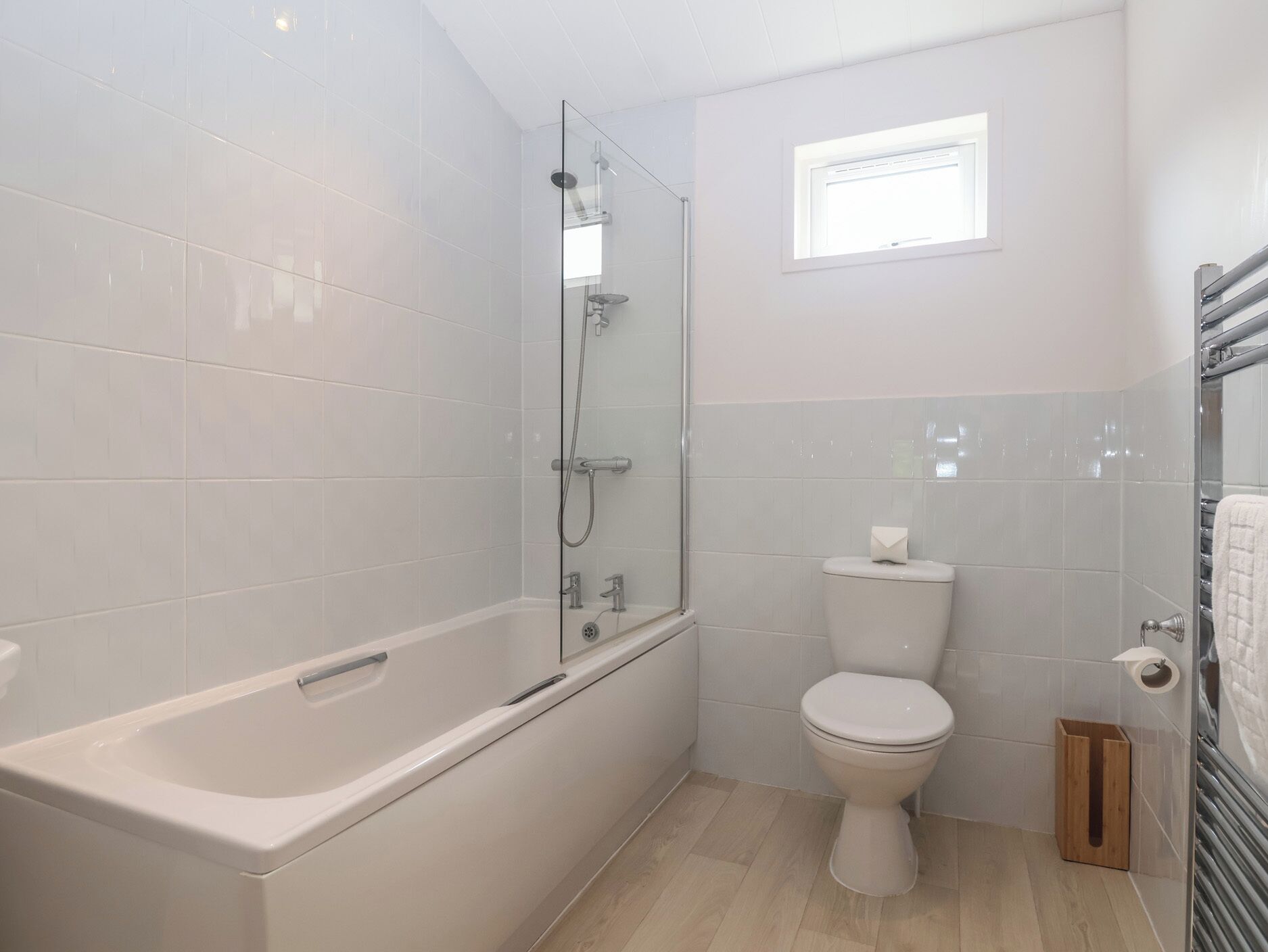 A bathroom with a bathtub, toilet, and a window.