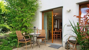 A patio with wicker chairs, a small table, and a bottle. - Apartment 'Marie' with Private Terrace and Wi-Fi (Bodman-Ludwigshafen)