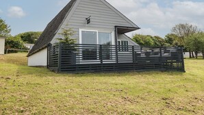 A single-story house with a sloped roof, a front porch with a black railing, and a small deck area. - La Bella Vista (Bude)