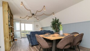 A dining area with a wooden table, brown chairs, and a potted plant. - La Bella Vista (Bude)