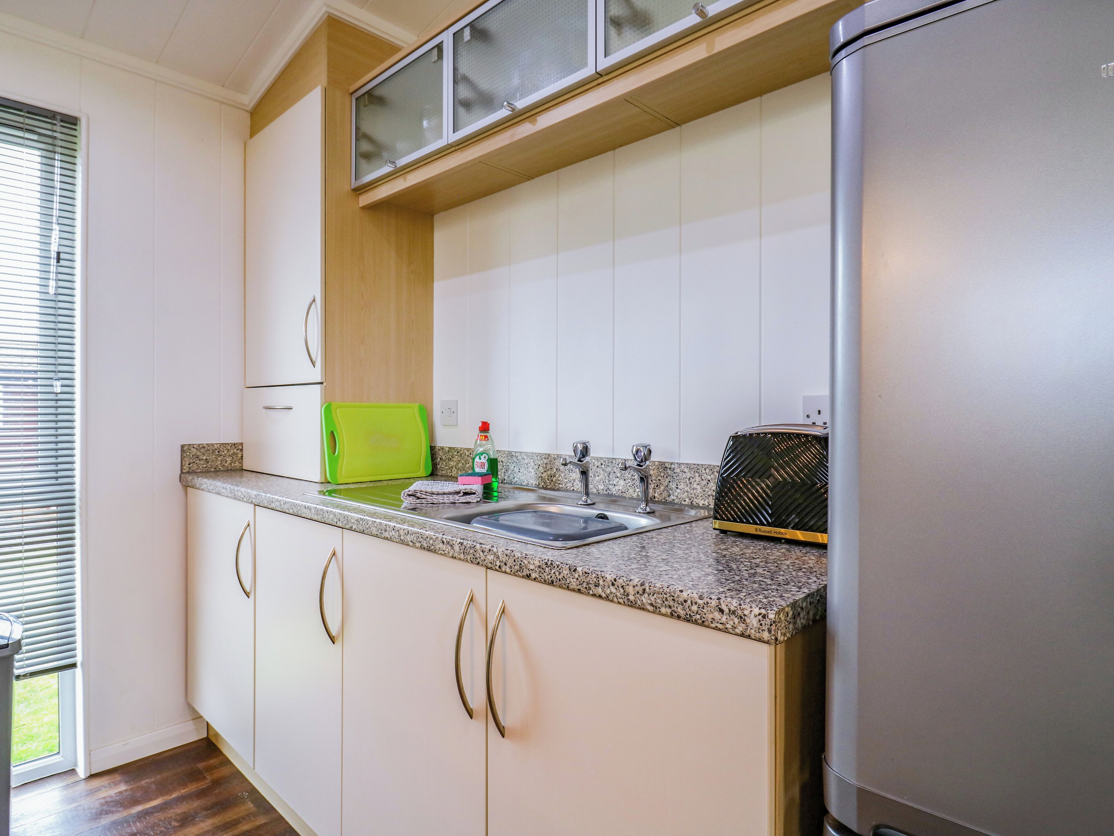 A modern kitchen with white cabinets, a granite countertop, and a stainless steel refrigerator.