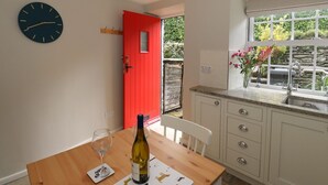 Une cuisine avec une table en bois, une bouteille de vin et une horloge au mur.