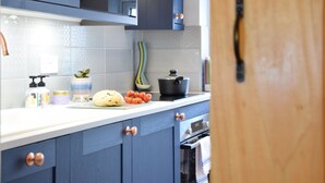 A modern kitchen with dark blue cabinets, a white countertop, and a stainless steel oven.