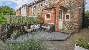 A house with a stone facade, a wooden deck, and a garden with lavender plants.