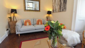 A living room with a sofa, a coffee table with a vase of flowers, a mirror, and two lamps. - Belmont House (Windermere)