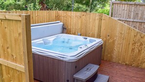 A hot tub in a wooden enclosure with a wooden deck and a step for access. - Edmunds Cottage (Bedale)