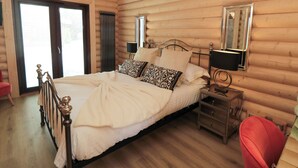 Een slaapkamer in chaletstijl met een bed, nachtkastje en spiegel.