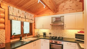 Cucina con mobili bianchi, una cappa in acciaio inossidabile, un lavello a due vasche e un forno a microonde.