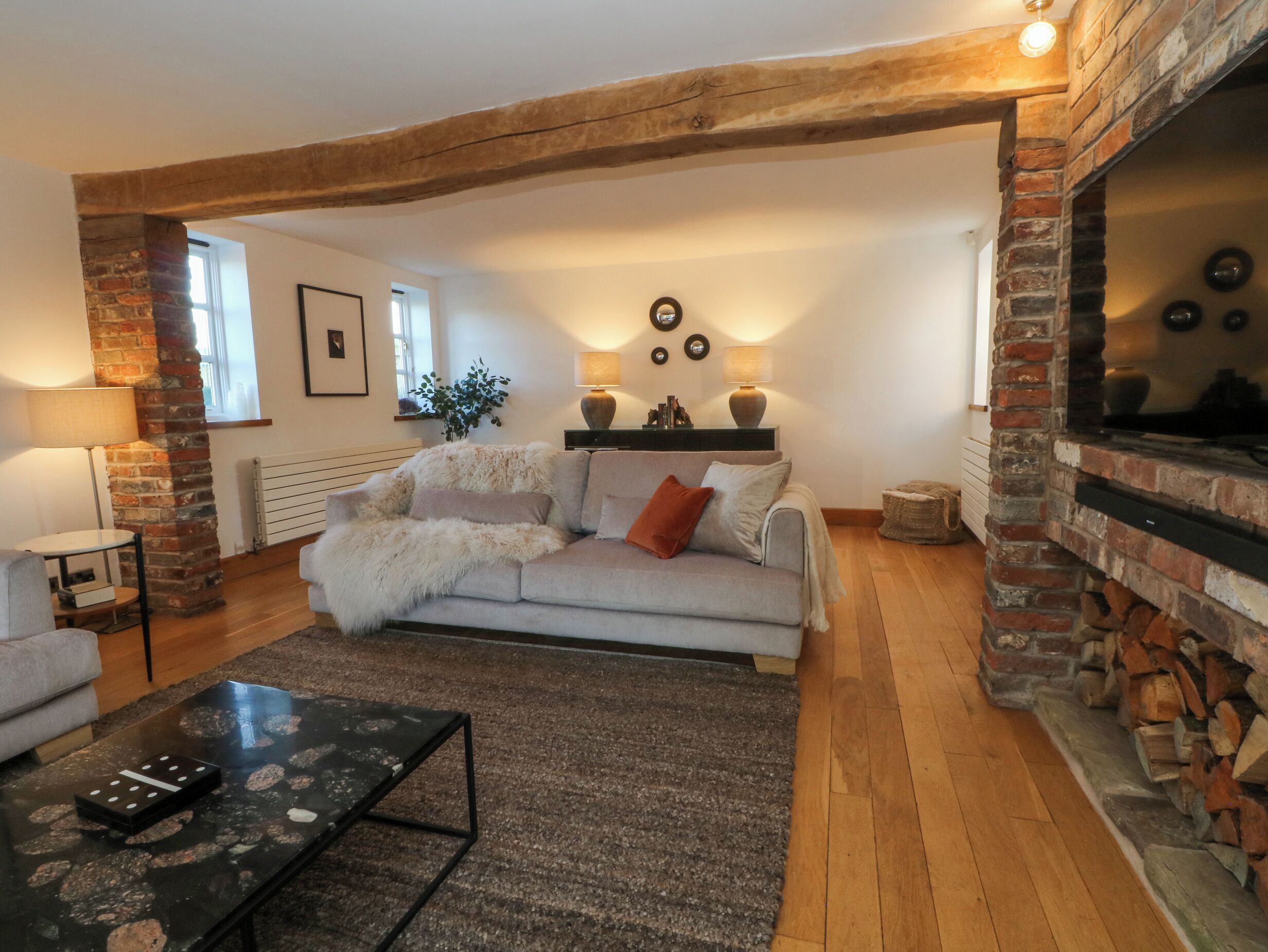 Una sala de estar acogedora con chimenea, un sofá, una mesa de centro y una lámpara.