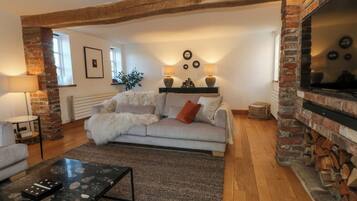Una sala de estar acogedora con chimenea, un sofá, una mesa de centro y una lámpara.