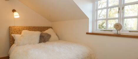 Un dormitorio con cama, ventana con vistas y lámpara de pared.