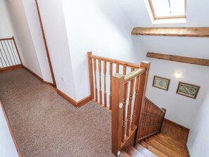 A wooden staircase with a handrail, carpeted floor, and a skylight above. - Middlefell View Cottage (Alston)
