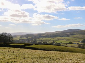 A rural landscape with rolling hills, fields, and a stone wall. - Middlefell View Cottage (Alston)