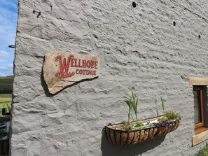 A stone wall with a sign reading 'WELLHOPE View Cottage.' - Wellhope View Cottage (Alston)