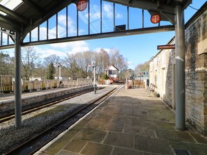 A railway station platform with stone flooring, a shelter, and a signal box.