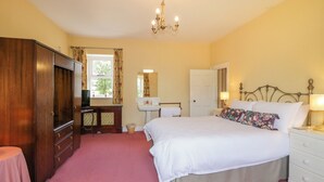Een slaapkamer met een groot bed, een dressoir, een kaptafel met spiegel en een kroonluchter.