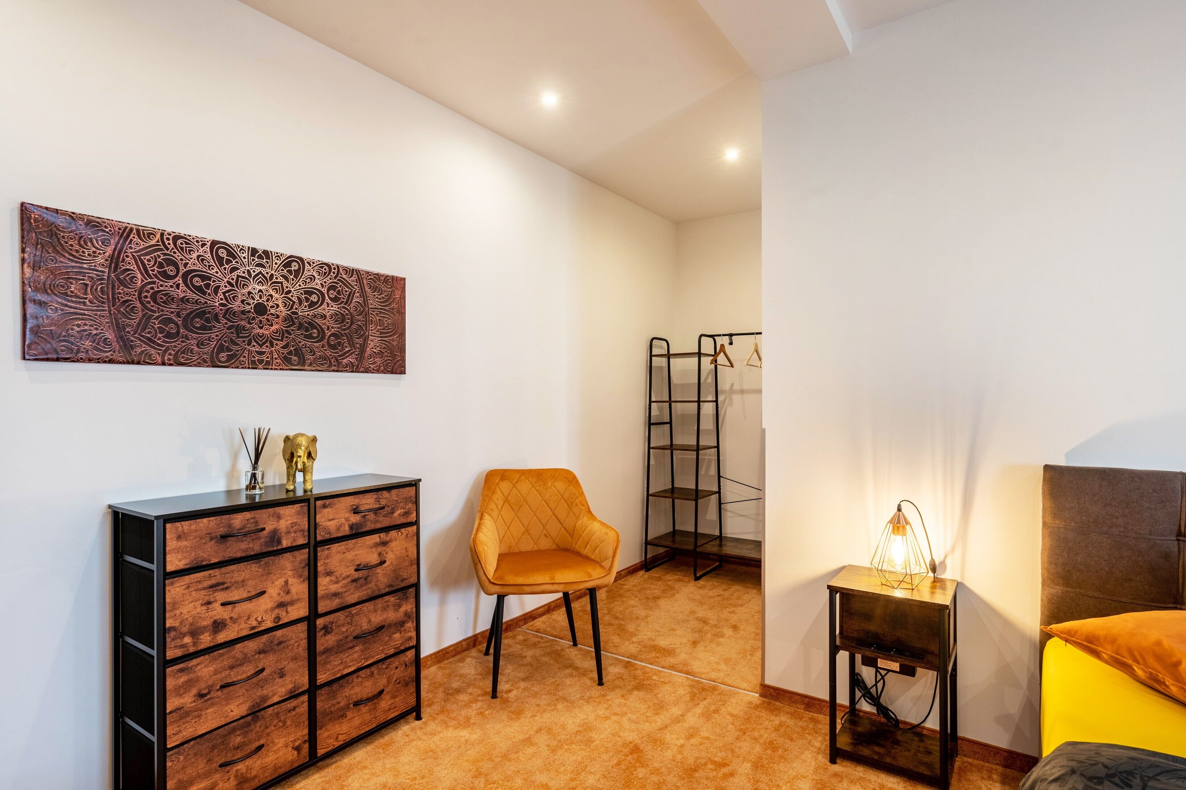 Une chambre à coucher comprenant un lit, une table de chevet, une chaise, une commode et une œuvre d’art murale.