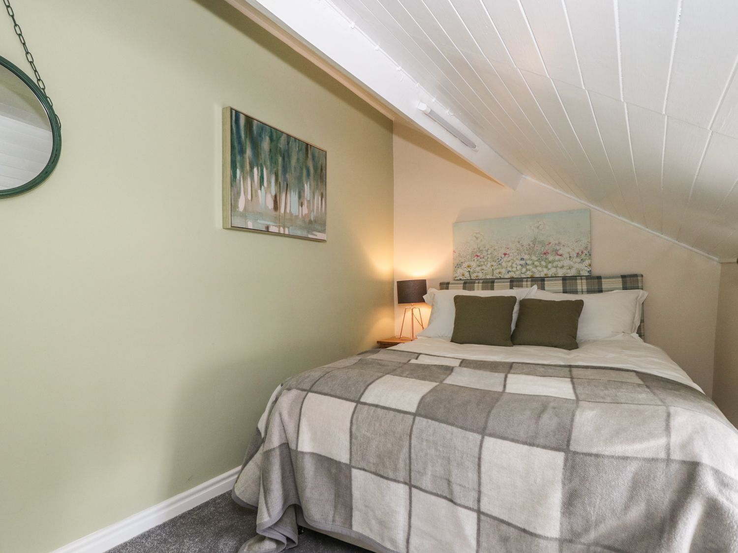 Une chambre à coucher avec un lit, un tableau, une lampe et un luminaire au plafond.