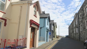 A street with buildings, including a blue house with a visible door and a signboard. - Captain's Rest (Porthmadog)