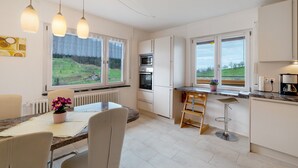 Eine moderne Küche mit Essbereich, großen Fenstern und Blick ins Freie.