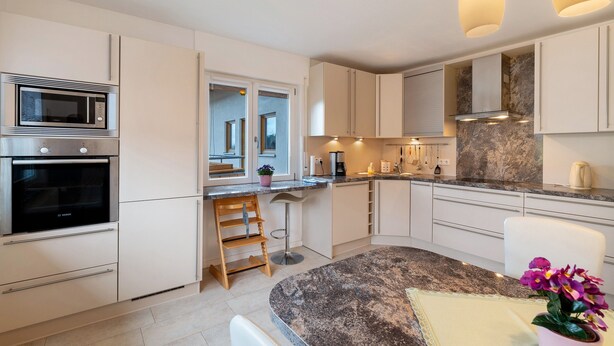 Eine moderne Küche mit eingebautem Backofen, Mikrowelle und einer Arbeitsplatte aus Granit.