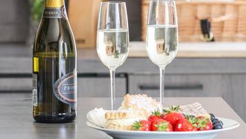 A bottle of Prosecco wine, two glasses of wine, and a plate with pastries and strawberries.