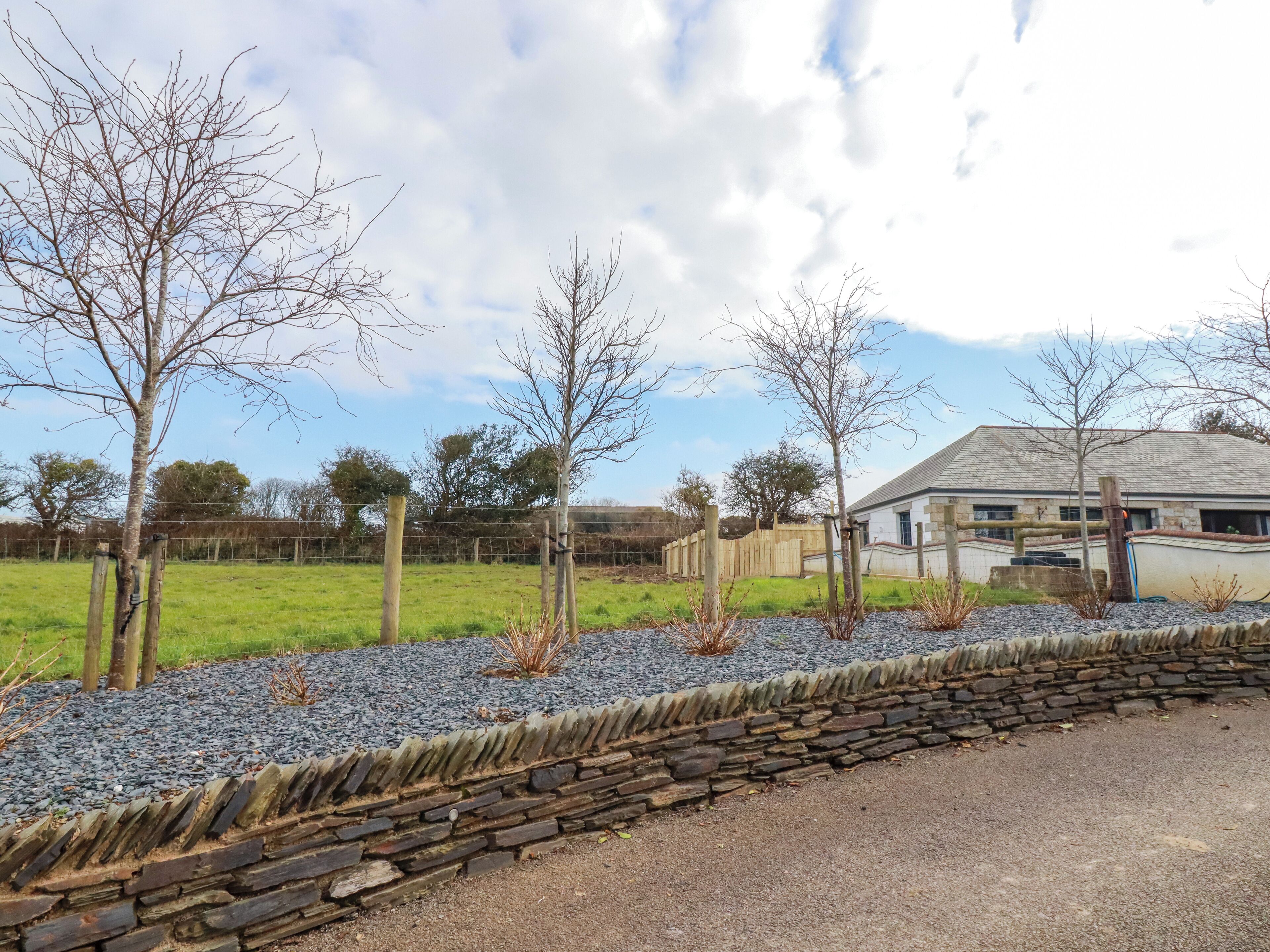 A stone wall with a gravel path leading to a building with a stone facade.