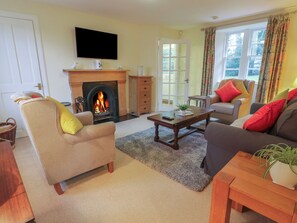 A living room with a fireplace, sofas, a coffee table, and a television. - Eagle Glen Cottage (Blairgowrie)