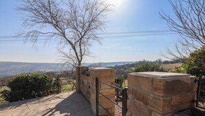 A stone pathway leading to a gated entrance with a view of rolling hills and a clear sky. - Roding Cottage (Whitby)