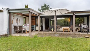 Una casa moderna con un porche cubierto, mobiliario exterior y una zona de barbacoa.