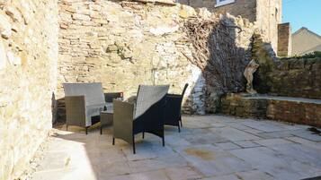 Un patio al aire libre con suelo de piedra y mobiliario de mimbre.